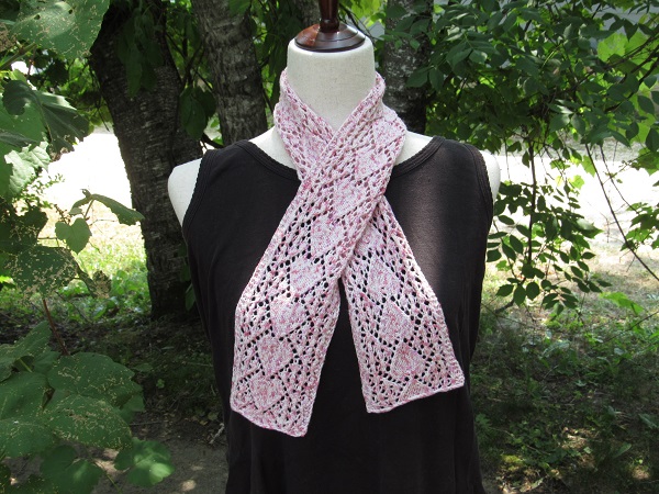 a white and pink speckled scarf with an arrow or heart theamed lace